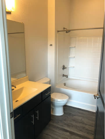 A white toilet sits in a bathroom next to a sink and bathtub.