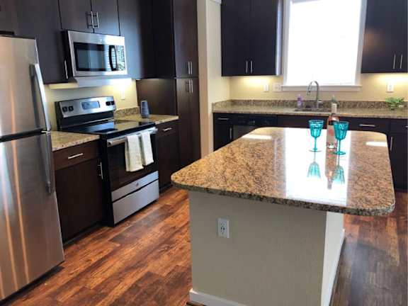 A kitchen with a granite countertop and stainless steel appliances.