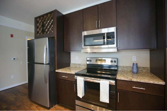 A kitchen with a stainless steel refrigerator, a microwave, and a stove with an oven.