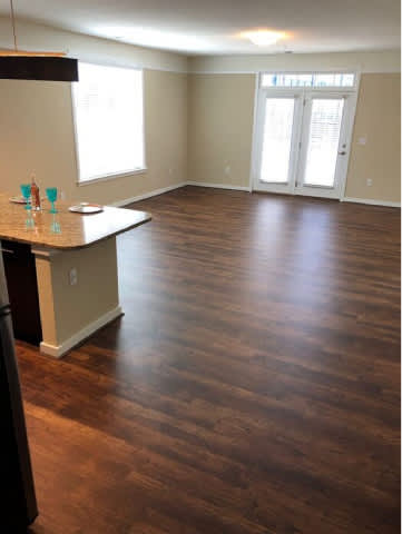 A room with wood flooring and a kitchen island.