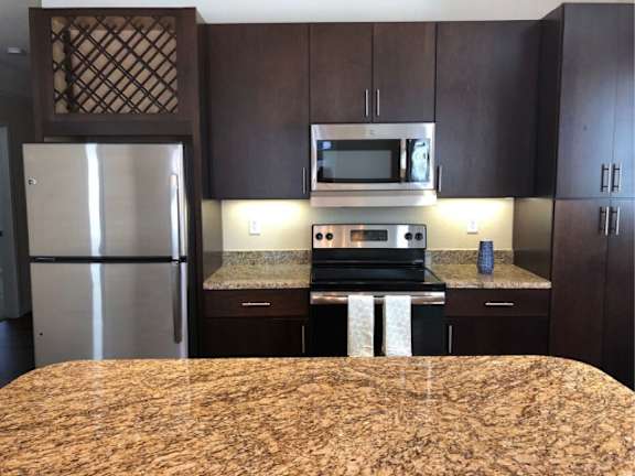 A kitchen with a granite countertop and stainless steel appliances.