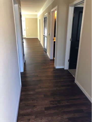 A long hallway with wood floors and white walls.