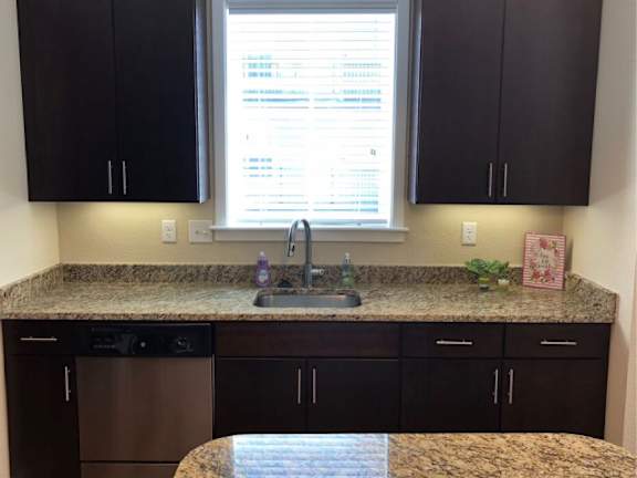 A kitchen with brown cabinets and granite countertops.