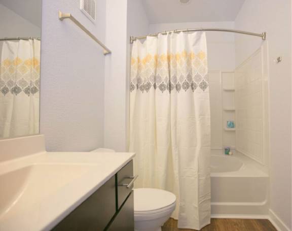 A white bathroom with a toilet, sink, and shower.
