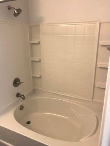 A white bathtub with a shower head and faucet.