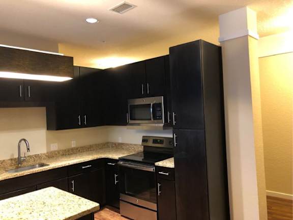 A kitchen with black cabinets and a granite countertop.