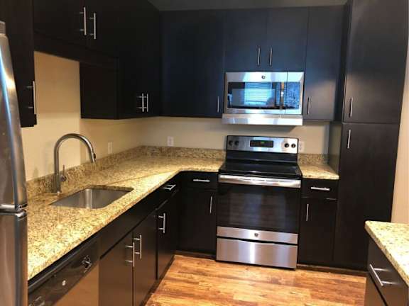 A kitchen with black cabinets and a granite countertop.