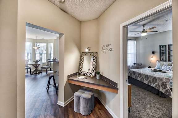A bedroom with a bed, a desk with a chair, and a mirror on the wall.