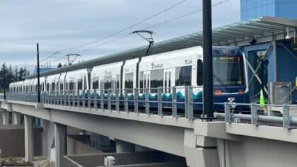 A train is on a bridge with a car behind it.