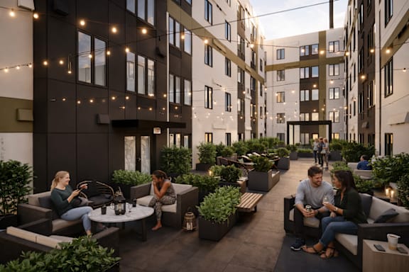 People are sitting and talking in a courtyard surrounded by buildings.