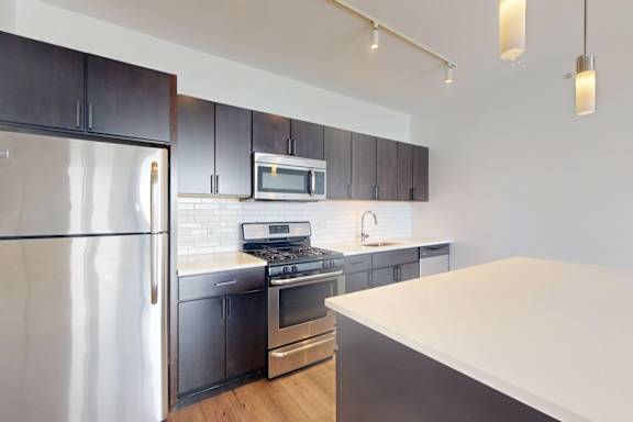 A modern kitchen with dark brown cabinets and stainless steel appliances.