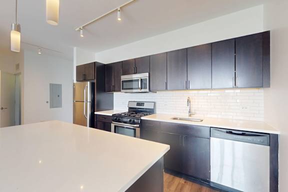 A modern kitchen with black cabinets and stainless steel appliances.