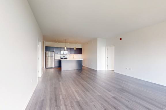 A spacious room with a kitchen area in the background.