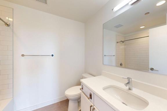 A white bathroom with a toilet, sink, and mirror.