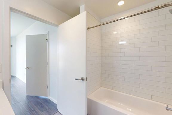 A white bathroom with a white tub and a white door.