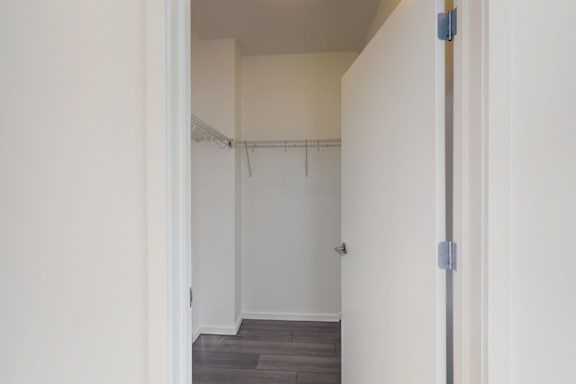 A white hallway with a grey floor and a white door.