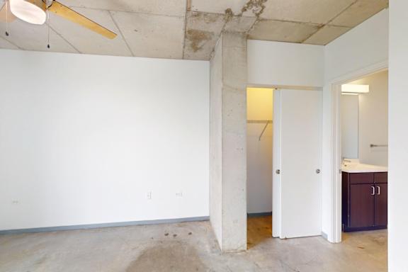 A room with a ceiling fan and a column in the middle.