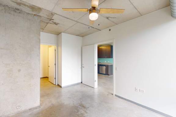 A room with a ceiling fan and concrete walls.