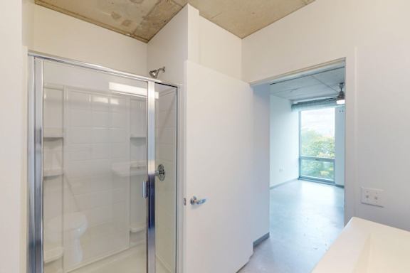 A white bathroom with a glass shower door and a white toilet.
