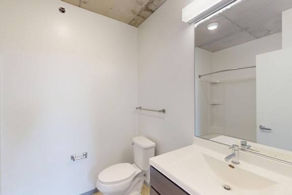 A white bathroom with a toilet, sink, and mirror.