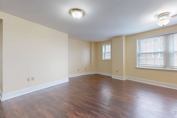 Empty room with wood flooring and two windows.