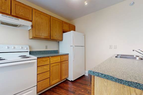 A kitchen with a white stove and wooden cabinets.