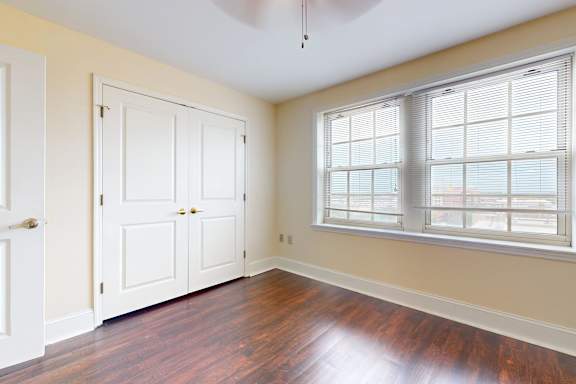 A room with a white door, two white cabinets, and a window with blinds.