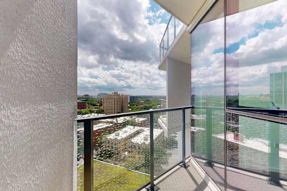 A balcony with a glass railing overlooking a cityscape.