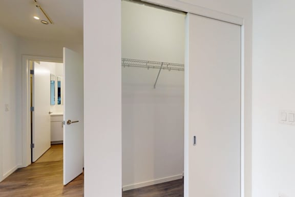 A white door with a glass window is in a white room.