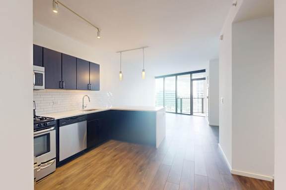 A kitchen with black cabinets and a white backsplash.