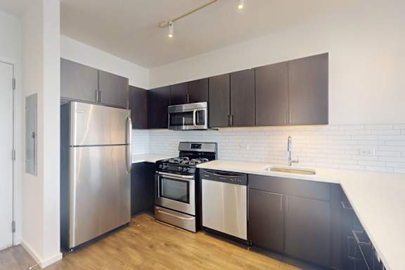 A modern kitchen with a stainless steel refrigerator, stove, and oven.