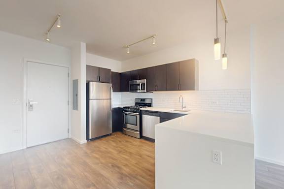 A kitchen with a white counter top and stainless steel appliances.