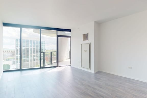 A room with a wooden floor and a door leading to a balcony.