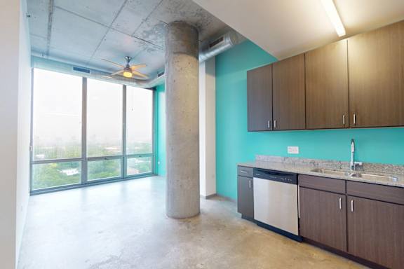 A kitchen with a blue wall and wooden cabinets.