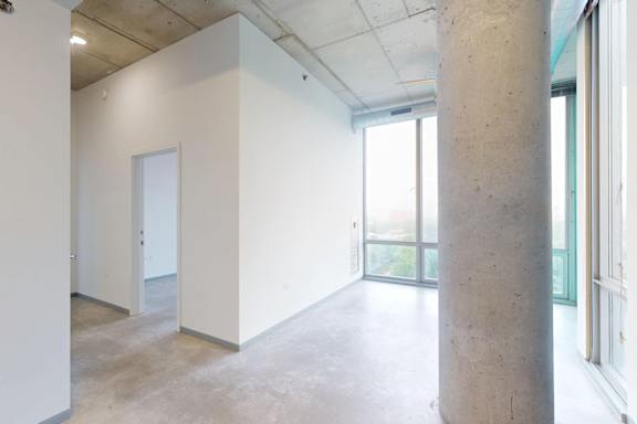 A large, empty room with a concrete pillar and a door.