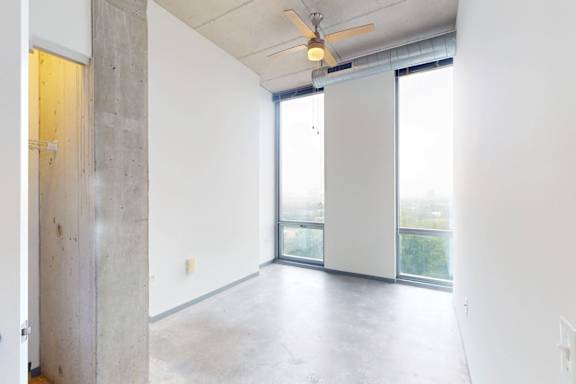 A room with a ceiling fan and sliding glass doors.