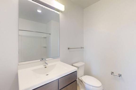 A white sink with a mirror above it and a toilet in the corner.