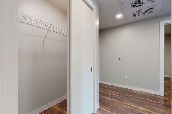 A white closet with a wooden floor and a white door.