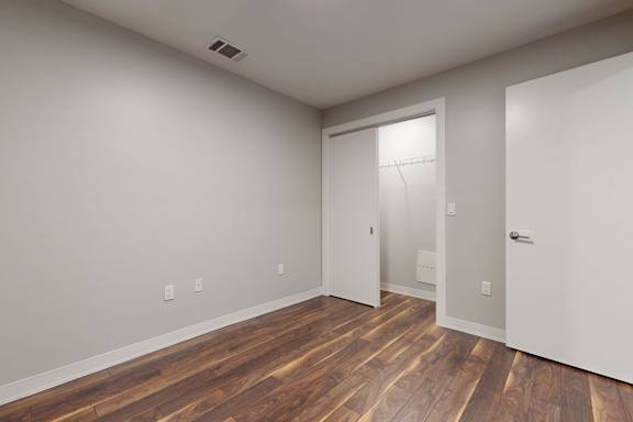 A room with a white door and a wooden floor.