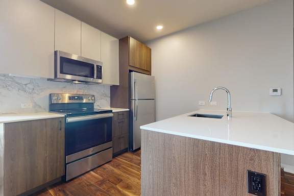 Floor Plan  A kitchen with a white counter top and wooden cabinets.