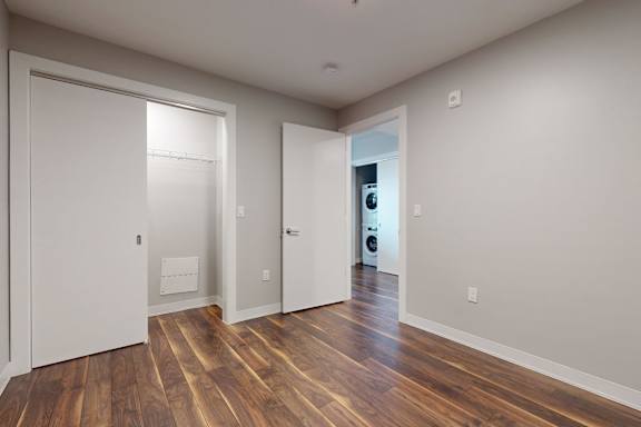 A room with a white door and a brown floor.