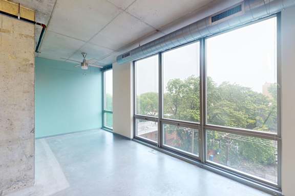 A room with a concrete wall and a ceiling fan.