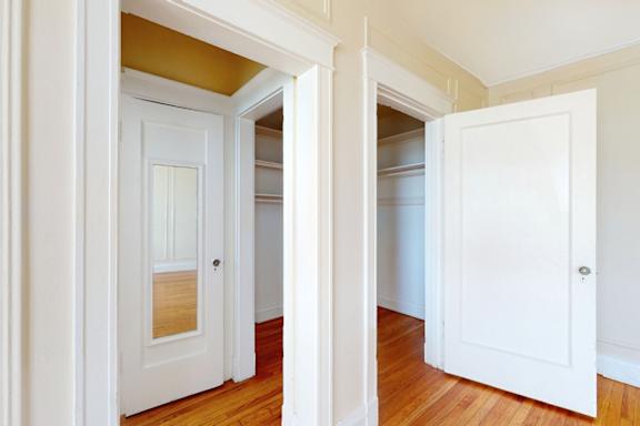A white door is open to a room with a wooden floor.