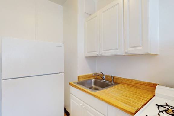 A white refrigerator sits next to a sink in a kitchen.