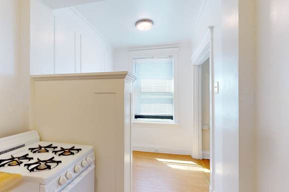 A white gas stove is in a kitchen with a window.