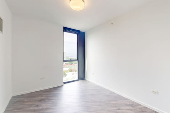A room with a sliding glass door and wooden flooring.