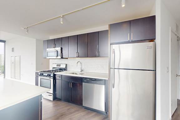 A kitchen with a white refrigerator, black cabinets, and a white countertop.