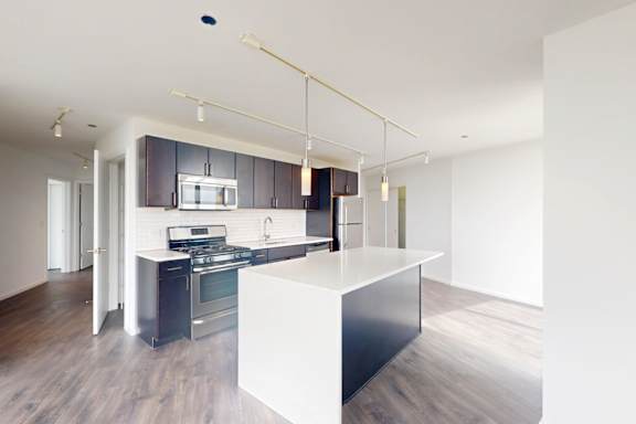 A modern kitchen with a white island and dark wood cabinets.