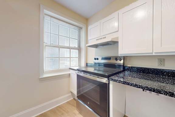 A kitchen with white cabinets and a black granite countertop.