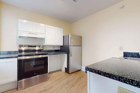 A kitchen with a black granite countertop and stainless steel appliances.